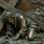 Relieve en bronce oscuro de Jesús cayendo bajo la cruz con corona de espinas y túnica de pliegues realistas.