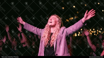 Mujer rubia adorando brazos abiertos blazer lavanda ojos cerrados canto luz rosa bokeh dorado multitud manos culto horizontal emotivo