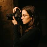 Mujer fotografa camara canon dslr lente profesional culto adoracion luces escenario produccion medios iglesia vertical oscuro