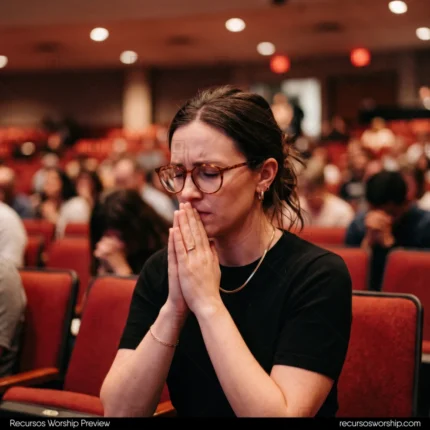 Mujer joven orando manos juntas gafas carey asientos rojos auditorio ojos cerrados intercesion fe cuadrado