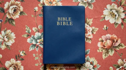 Biblia cerrada azul marino con letras doradas BIBLE sobre tela floral estampada en flores rosas y blancas vista cenital horizontal