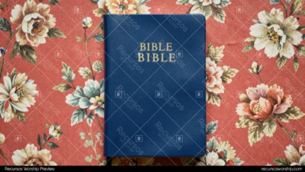 Biblia cerrada azul marino con letras doradas BIBLE sobre tela floral estampada en flores rosas y blancas vista cenital horizontal