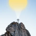 Cruz pequeña cima roca montañosa escarpada gran sol dorado brillante exactamente detras irradiando luz arriba cielo azul claro degradado vertical formato movil espectacular