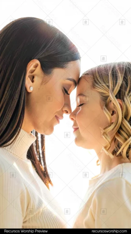 Madre morena cabello oscuro liso hija joven rubia ondulada frentes casi tocandose ojos cerrados sueteres blancos cuello alto fondo blanco sobreexpuesto luminoso vertical etéreo