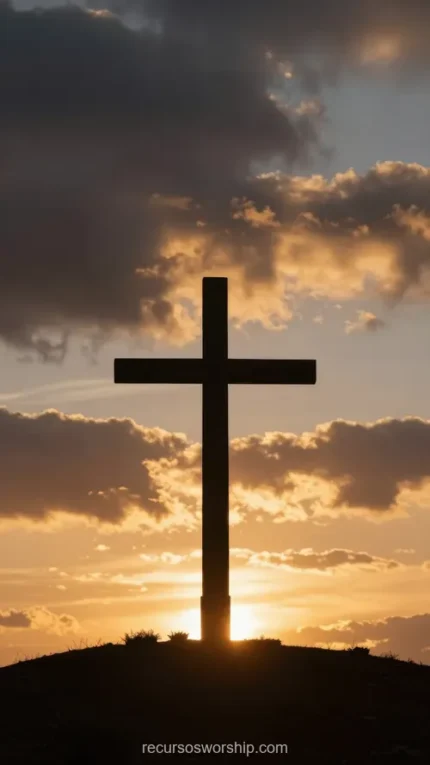 Cruz grande en silueta oscura sobre cielo de atardecer dramático con nubes doradas y naranjas y halo de luz solar detrás de la base en colina