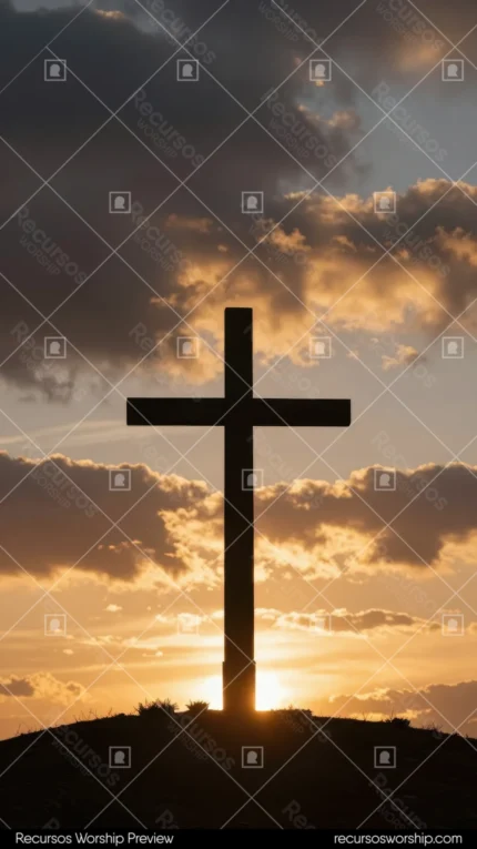 Cruz grande en silueta oscura sobre cielo de atardecer dramático con nubes doradas y naranjas y halo de luz solar detrás de la base en colina