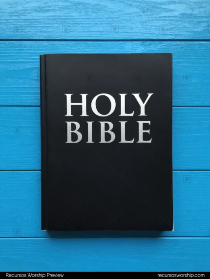 Holy Bible negra mate con letras blancas en relieve sobre tablones de madera pintada azul eléctrico brillante vista cenital