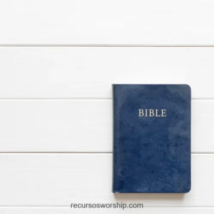 Biblia cerrada azul marino con letras doradas en esquina inferior derecha sobre tablones de madera blanca con espacio negativo cenital