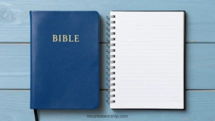 Biblia azul marino cerrada con letras doradas junto a cuaderno espiral abierto en blanco sobre tablones de madera turquesa claro cenital
