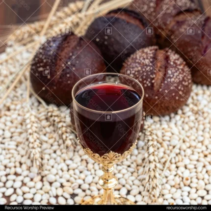 Copa vino dorada ornamentada vino tinto oscuro granos trigo dispersos panes artesanales oscuros espigas trigo mesa madera calida cuadrado rustico tradicional santa cena eucaristia