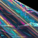Lamina celofan holografico arrugado iridiscencia espectral cian azul magenta rosa dorado naranja fondo negro horizontal detalle iridiscente cinematografico especular material plastico textura diseno overlay