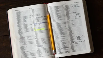 Biblia abierta con páginas anotadas en márgenes y texto resaltado en amarillo fluorescente con lápiz amarillo sobre madera oscura cenital