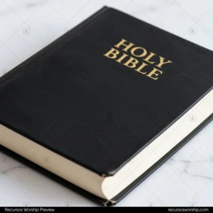 Holy Bible negra tapa dura con letras doradas y cantos crema en ángulo de tres cuartos sobre superficie mármol blanco con venas grises