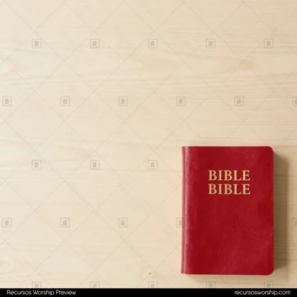 Biblia de cuero rojo con letras doradas en esquina inferior derecha sobre tablones de madera pino clara con gran espacio negativo cenital