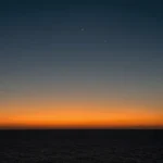 Paisaje marino nocturno fotorrealista franja naranja dorado horizonte cielo azul marino oscuro negro estrellas mar oscuro vertical contemplativo solemne esperanza oscuridad ministerial