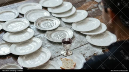 Hombre espaldas sosteniendo copa vino tinto pan blanco mesa madera multiples platos blancos vacios alineados horizontal natural intimo preparacion santa cena congregacional ministerial