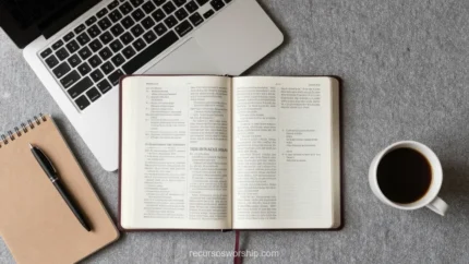 Escritorio con Biblia abierta al centro laptop gris cuaderno espiral marrón y taza de café sobre concreto gris texturizado vista cenital