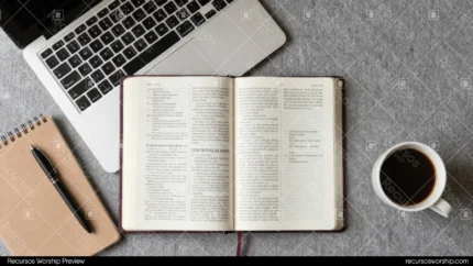 Escritorio con Biblia abierta al centro laptop gris cuaderno espiral marrón y taza de café sobre concreto gris texturizado vista cenital