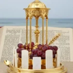 Custodia copón liturgico dorado ornamentado templete columnatas cruz dorada uvas obleas blancas espiga trigo biblia abierta fondo mar azul vertical devocional solemne eucaristia clasica