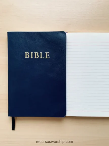 Biblia azul marino cerrada con letras doradas junto a cuaderno abierto de hojas rayadas en blanco sobre madera clara beige cenital