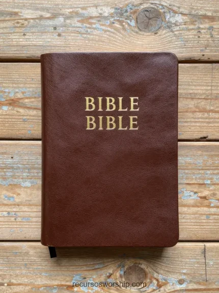 Biblia de cuero marrón cálido con letras doradas BIBLE en dos líneas sobre tablones de madera exterior gris blanqueado rústico cenital