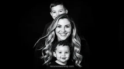 Retrato blanco negro madre rubia ondulada sonriendo hijo mayor detras menton apoyado cabeza bebe rizado sonriendo primer plano fondo negro profundo vertical dramatico