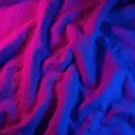 Fotografia macro vertical tela arrugada algodon toalla iluminacion dramatica rosa magenta azul violeta profundo pliegues sombras relieves plasticidad tactil neon diseno